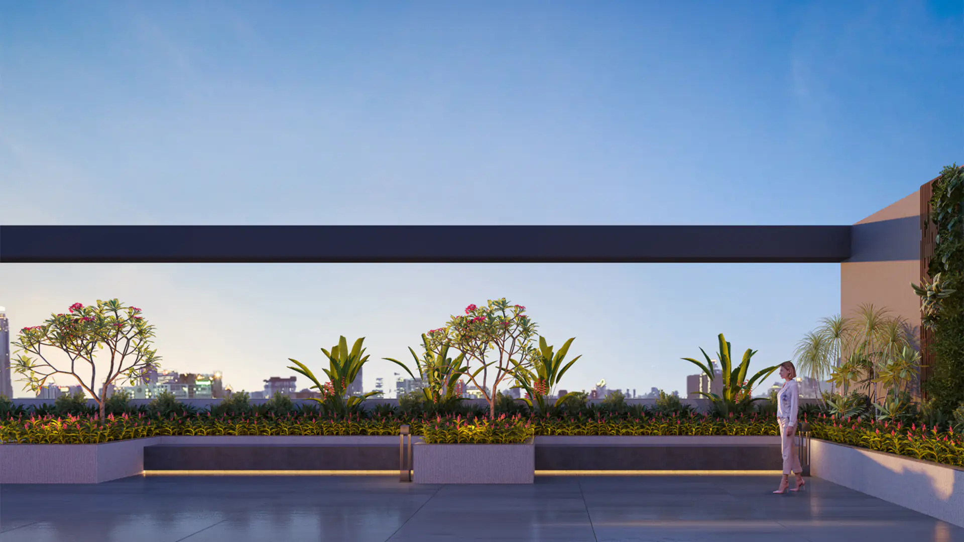 The landscaped rooftop terrace at Sun Garnet at dusk, with planters, lit seating and the city skyline beyond